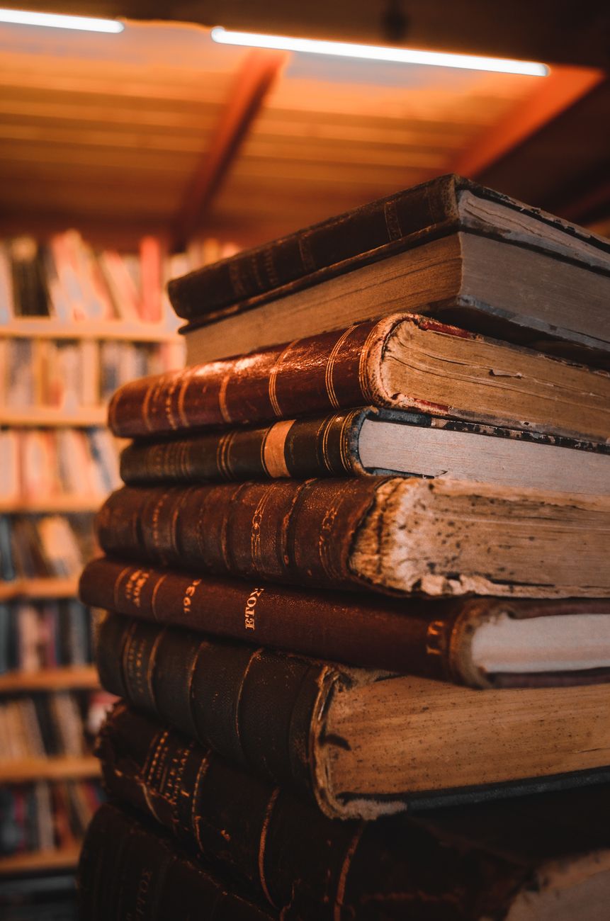 A stack of vintage leather-bound books in warm library light — the binding detail archivists look for when reading a maker's mark.