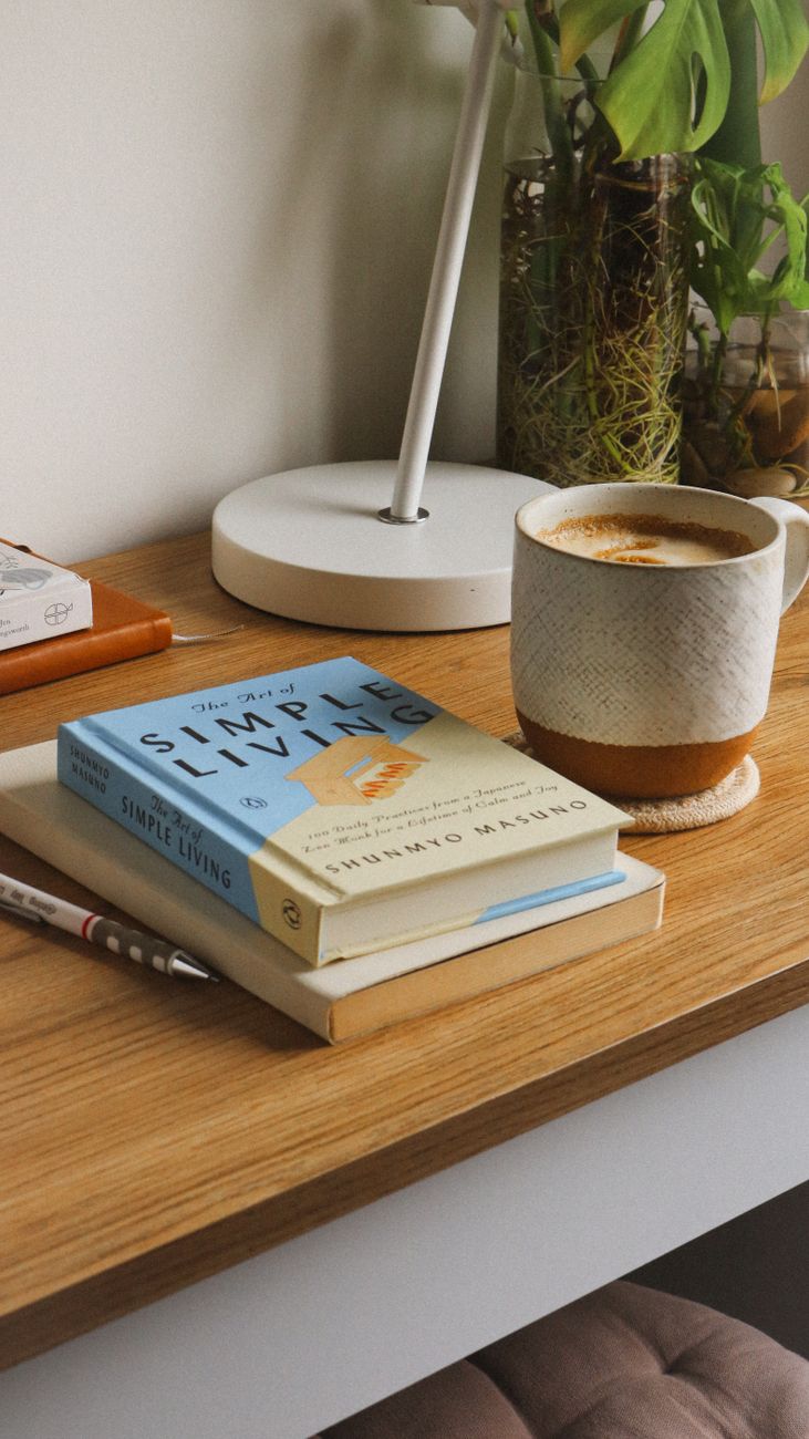 A quiet, uncluttered desk corner with a single lamp, a notebook, and a cup — a scene with nothing bought for the look of the scene.