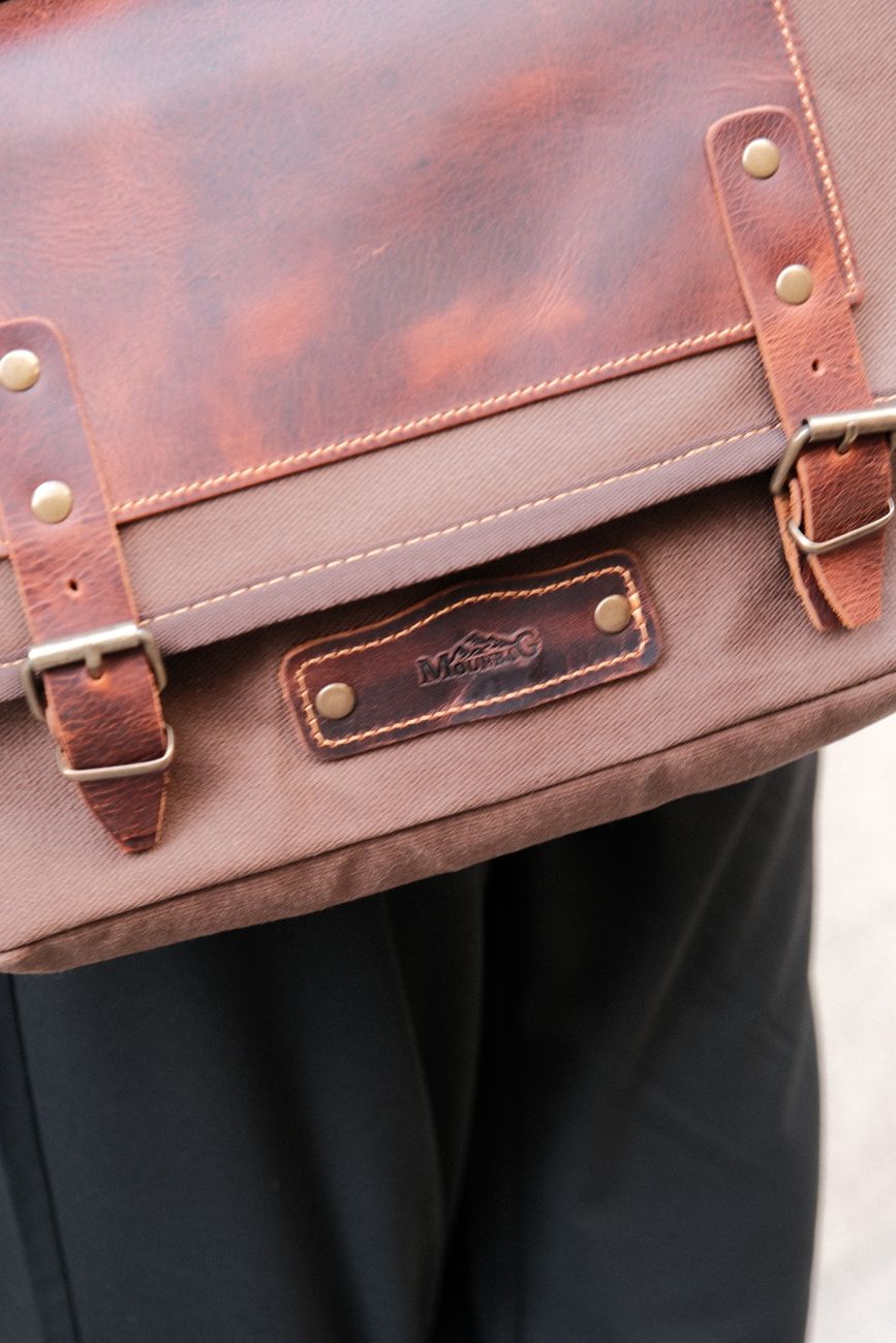 A single well-made object — a leather-and-brass detail on a bag or a chair arm — photographed close, without a styled backdrop.